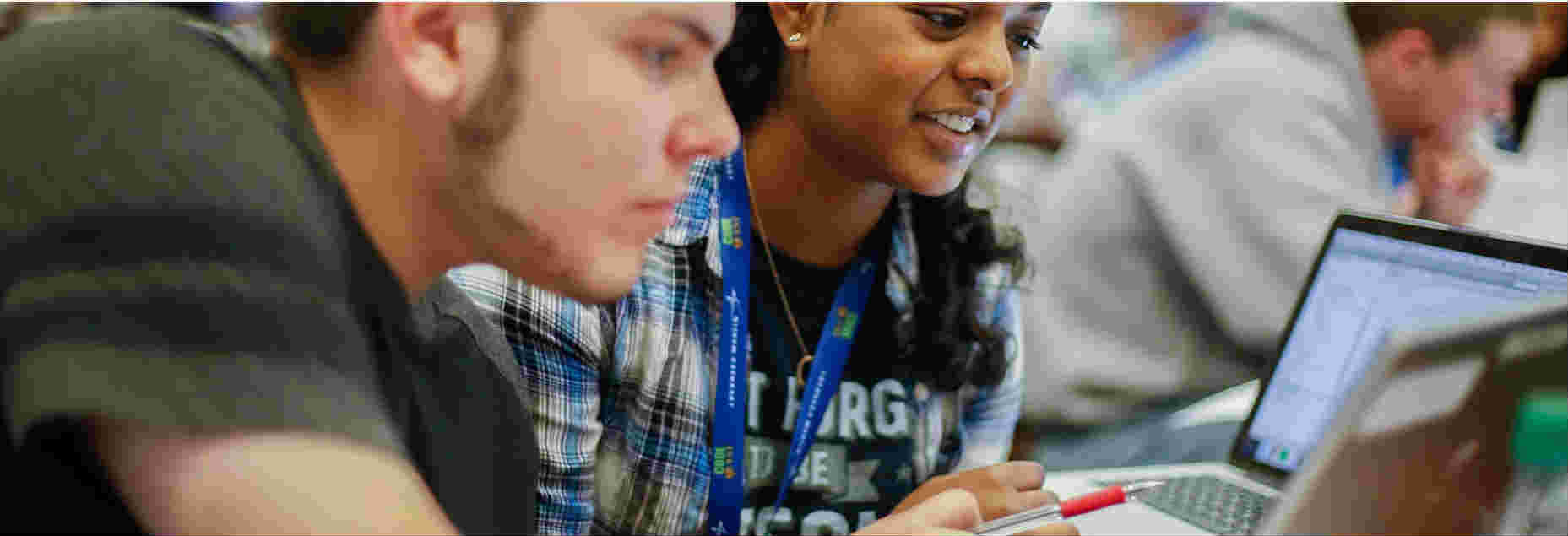 Two students working on laptops competing at the CodeQuest coding competition